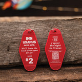 Front and back of a red Inn Uranus vintage motel keychain displayed on wood from Uranus Fudge Factory.