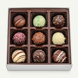 Open 9-piece Uranus truffle box showing nine assorted milk, dark, and white chocolate truffles with drizzles, toffee pieces, and sprinkles