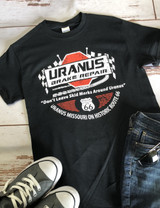 Uranus Brake Repair T-Shirt lying flat on a wooden table with sneakers and jeans. 
