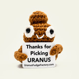 Light brown Emotional Support Poop crochet stuffie holding a Thanks for Picking Uranus sign, front view