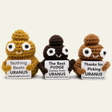Yellow, dark brown, and light brown Emotional Support Poop crochet stuffies holding Uranus Fudge Factory signs in a row