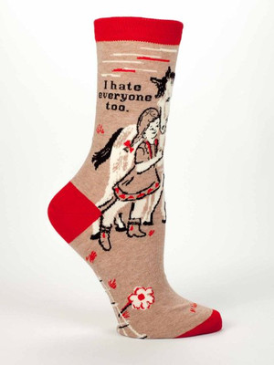 A single tan crew sock displayed against a plain white background. The sock features bright red accents on the toe, heel, and top cuff. Knit into the side is a vintage-style illustration of a smiling little girl with pigtails warmly hugging a white pony. Scattered around the bottom are small red and white flowers. Above the girl and horse, black text reads: "I hate everyone too."