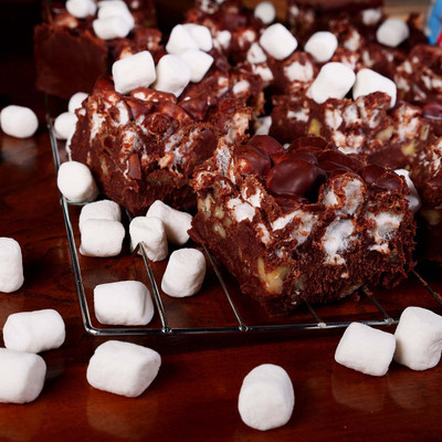 Freshly cut Rocky Road Fudge from Uranus, loaded with nuts and marshmallows, cooling on a wire rack.