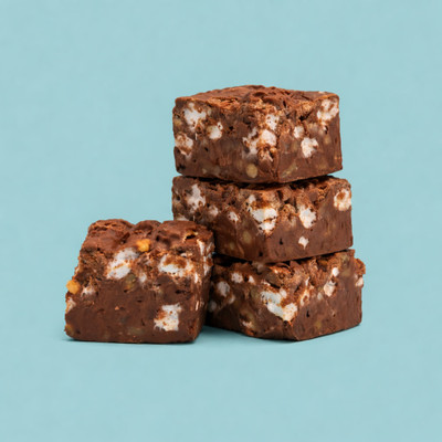 A stack of three square pieces of rocky road fudge studded with marshmallows and nuts, with a fourth piece leaning against the base, set against a solid light blue background.