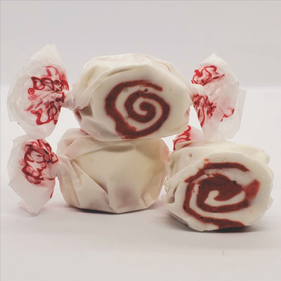 White and red swirled red velvet cake gourmet salt water taffy pieces stacked on a white background
