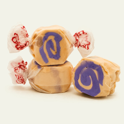 Three colorful wrapped PB&J saltwater taffy candies stacked together on a plain white background by Uranus Fudge Factory.