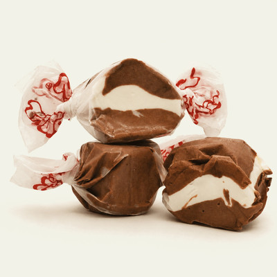 Three colorful wrapped cookies and cream saltwater taffy candies stacked together on a plain white background by Uranus Fudge Factory.
