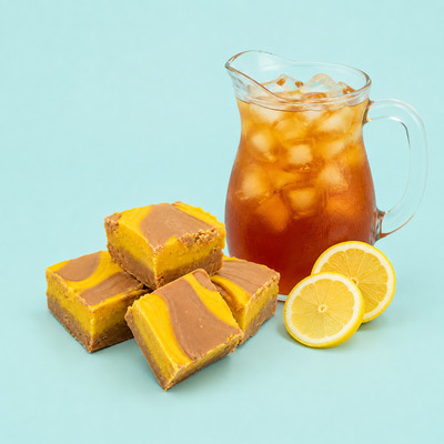 Squares of Lemon Iced Tea Fudge beside a pitcher of iced tea and fresh lemon slices