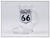 A clear glass souvenir shot glass shaped like a boot with a handle featuring a black and white Route 66 shield