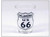 A clear glass souvenir shot glass featuring a black and white Oklahoma US 66 highway shield design