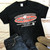 Black Uranus Fudge Packer t-shirt laid flat next to jeans and boots.