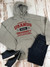 A grey graphic hoodie displayed on white wood with blue jeans and sneakers from Uranus Fudge Factory.