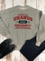 A flat lay of a casual outfit featuring a heather gray crewneck sweatshirt with a "Property of Uranus University" graphic in distressed red and navy ink.