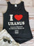 A flat lay of the black I Heart Uranus tank top paired with white shorts and sunglasses