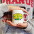 A person holding a white Uranus Gas 'N Lube Company novelty mug from Uranus Fudge Factory.
