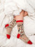 A person wearing the tan "I hate everyone too" horse novelty socks while lounging under a white duvet.