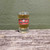 A single souvenir Uranus Fudge Packers Union shot glass filled with an amber beverage on a rustic wood surface