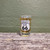 A collectible Uranus US 66 highway route shield shot glass filled with cider on a rustic wood plank background