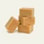 A stack of three square pieces of peanut butter fudge, with a fourth piece leaning against the base, set against a solid off-white background.