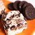 Rich Cookies and Cream Fudge from Uranus surrounded by whole chocolate sandwich cookies on a wooden cutting board.