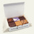 A six-piece Uranus fudge sampler pack inside a white box lined with parchment paper, featuring popular flavors from the Uranus Fudge Factory.
