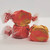 Three pieces of pink and orange swirled saltwater taffy are displayed against a white background, with two pieces stacked and one sitting to the side, all partially wrapped in wax paper with red twisted ends.