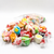 One-pound bag of Uranus Fudge Factory saltwater taffy variety mix tipped on its side with assorted individually wrapped taffy pieces spilling out in front, including blue, green, orange, yellow, pink, red, and chocolate-swirl flavors on a clean white background.