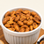 Smoky BBQ Redneck Nutz seasoned peanuts in a white bowl on a wooden board.
