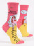 Pink and yellow novelty crew socks featuring a unicorn illustration and funny quote on a solid white background.