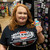 A woman holding a round space rocket souvenir logo vinyl sticker inside the Uranus Fudge Factory store