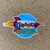 Die cut round space rocket cartoon souvenir sticker on a wood background from Uranus Fudge Factory