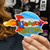 Close up view of a hand holding a round space rocket cartoon logo sticker from Uranus Fudge Factory