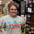 A woman holding a white Uranus US 66 highway shield sticker inside the Uranus Fudge Factory store