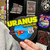 A hand holding a round Uranus Missouri logo souvenir magnet from Uranus Fudge Factory