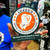 Close up view of the dark green and orange Uranus Dental and Proctology Clinic sticker from Uranus Fudge Factory