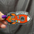 Orange rocket ship sticker held by a hand with purple nail polish against a dark cloth backdrop by Uranus Fudge Factory.