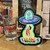 Alien UFO sticker displayed on a wooden shelf next to a souvenir shot glass at Uranus Fudge Factory.