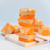 Orange creamsicle fudge stacked on a serving board with a light blue backdrop by Uranus Fudge Factory.