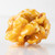 Macro close-up of a single glossy fresh buttery caramel corn piece on a white background by Uranus Fudge Factory.