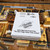 White Uranus Fudge Factory & General Store one-pound fudge box sitting on a glass display case above slabs of fudge, with the rocket logo and the tagline "The Best Fudge Comes From Uranus."