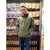 Man modeling an olive green hoodie with a small chest logo inside the Uranus Fudge Factory retail store.