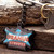 Uranus Liquors retro sign keychain attached to keys resting on weathered wood from Uranus Fudge Factory.