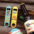 Two novelty metal bottle openers displayed on wood next to a root beer bottle from Uranus Fudge Factory.