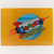 A rectangular yellow tin sign featuring the "Uranus Fudge Factory & General Store" logo. The design includes a colorful retro rocket ship flying across a blue moon, with the word "URANUS" in large, multi-colored block letters. Small pre-drilled holes are visible in the corners for mounting.