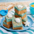 Salted caramel coconut fudge stacked on a blue plate with a beach towel, toy sand scoop, and seashell candies