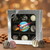 Assorted gourmet chocolate truffles in a 9-piece silver gift box from Uranus Fudge Factory, featuring milk, dark, and white chocolate truffles with drizzles and nut toppings on a wooden surface.