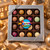 Uranus Fudge Factory 16-piece assorted chocolate truffle gift box in silver window box, surrounded by gold ribbon and Christmas ornaments