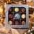Uranus Fudge Factory 9-piece assorted chocolate truffle gift box in silver window box with Christmas lantern, gold star, and snowflake ribbon
