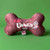 Brown plush bone dog toy with “Eat Uranus (fudge)” text and cartoon graphic on green background