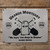 Uranus Mortuary 12x16 embossed metal sign with crossed shovels, RIP tombstone, and "We bury 'em deep in Uranus" tagline, mounted on a rustic wood plank wall.